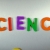 Hand Writes Science with Fridge Magnets Close-Up