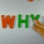 Hand Writes Why with Fridge Magnets Close-Up